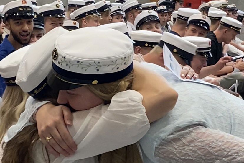 Glade og lettede studenter deler glæden med hinanden under dimissionen.