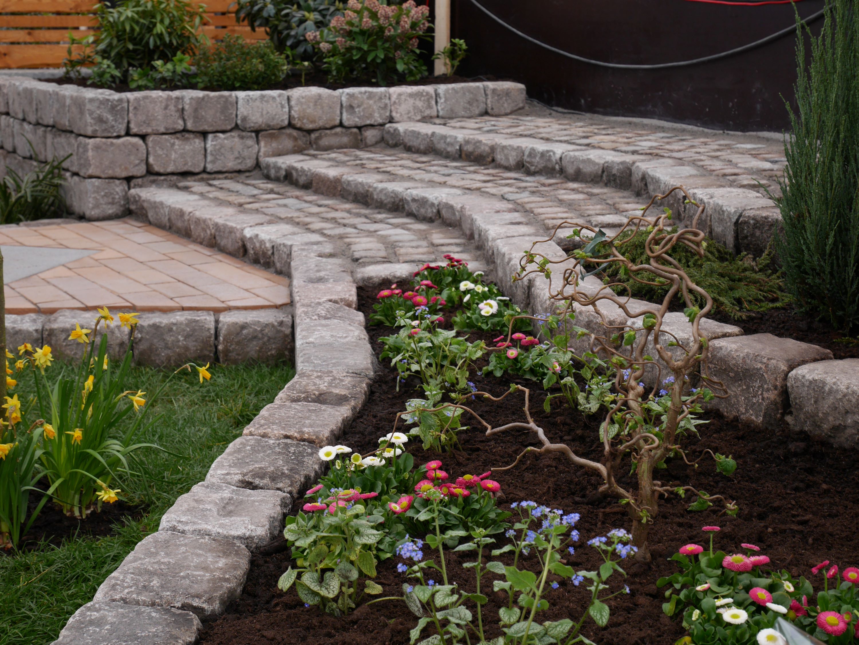 Nogle anlægningsgartnerelever har skabt et smukt uderum ved at anlægge blomsterbede og trappetrin i brosten