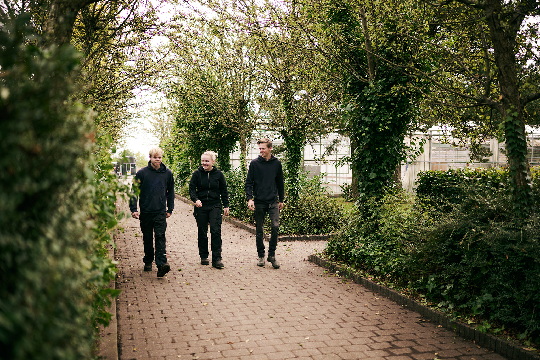Nogle af eleverne på Hansenbergs adresse i Vranderup er på vej fra parkeringspladsen og går forbi drivhusene hen til undervisningsbygningerne.