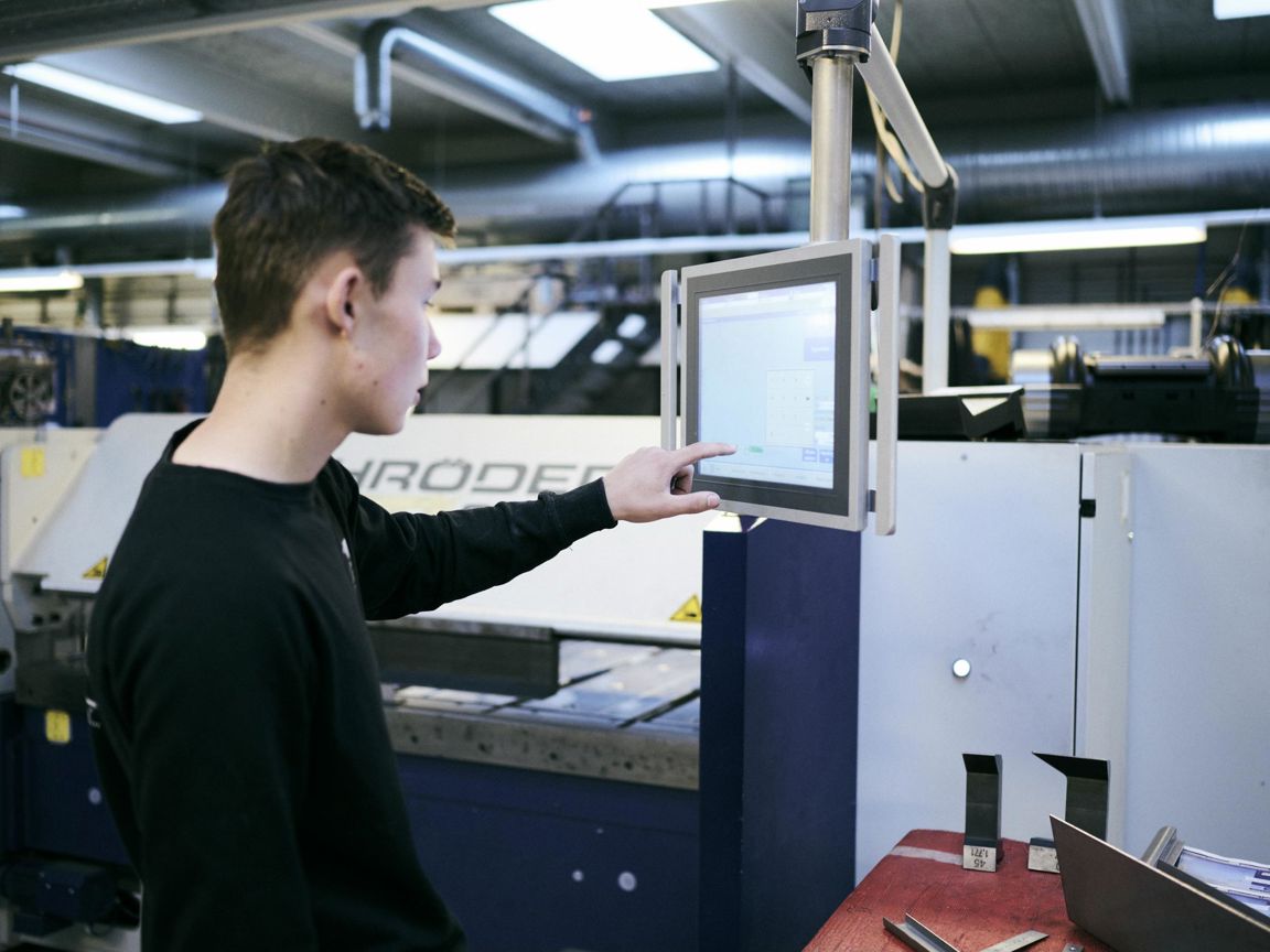 En smedeelev programmerer en bukkemaskine på Hansenbergs smedeværksted.