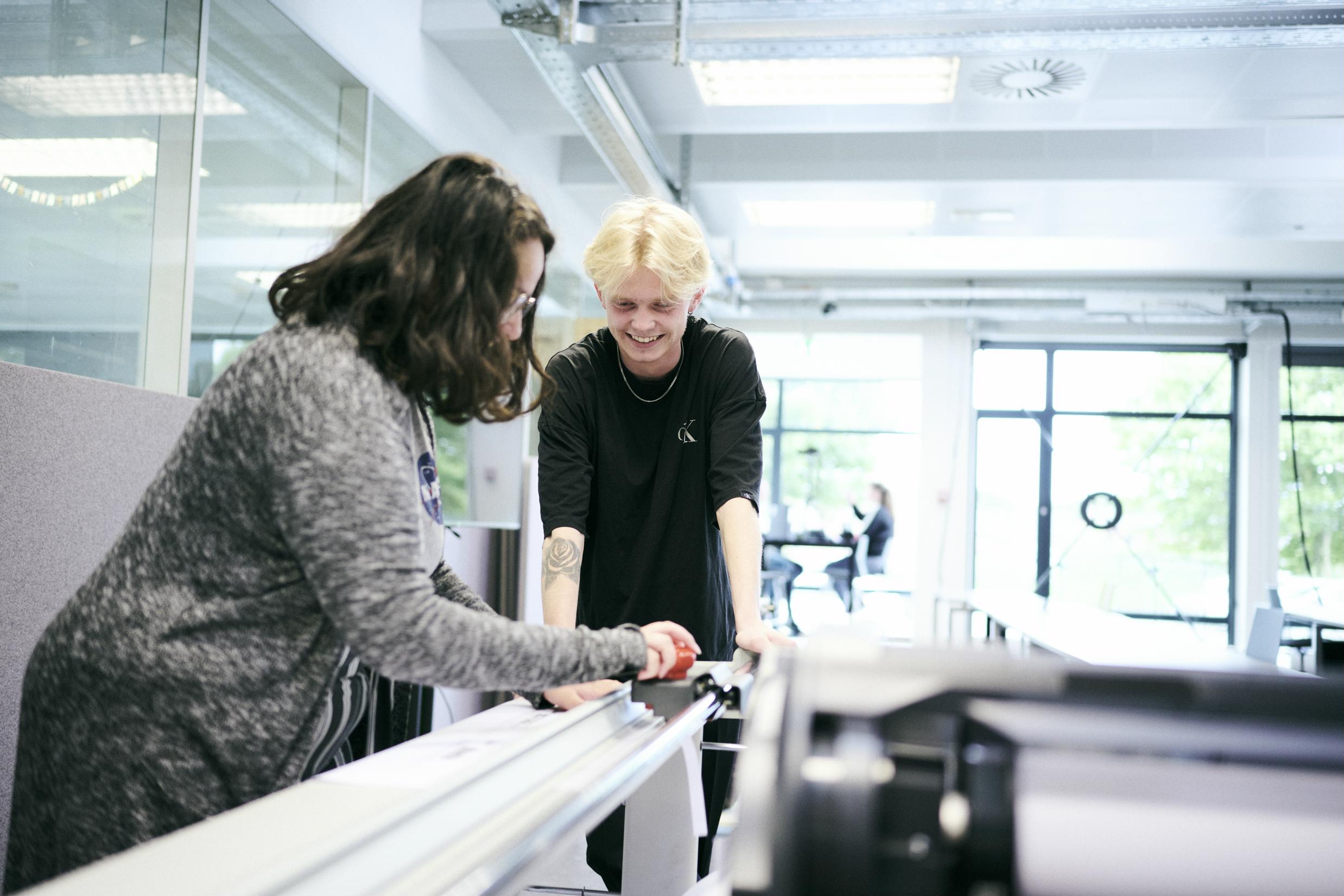 2 elever på uddannelsen til teknisk designer skærer en hustegning i storformat til.