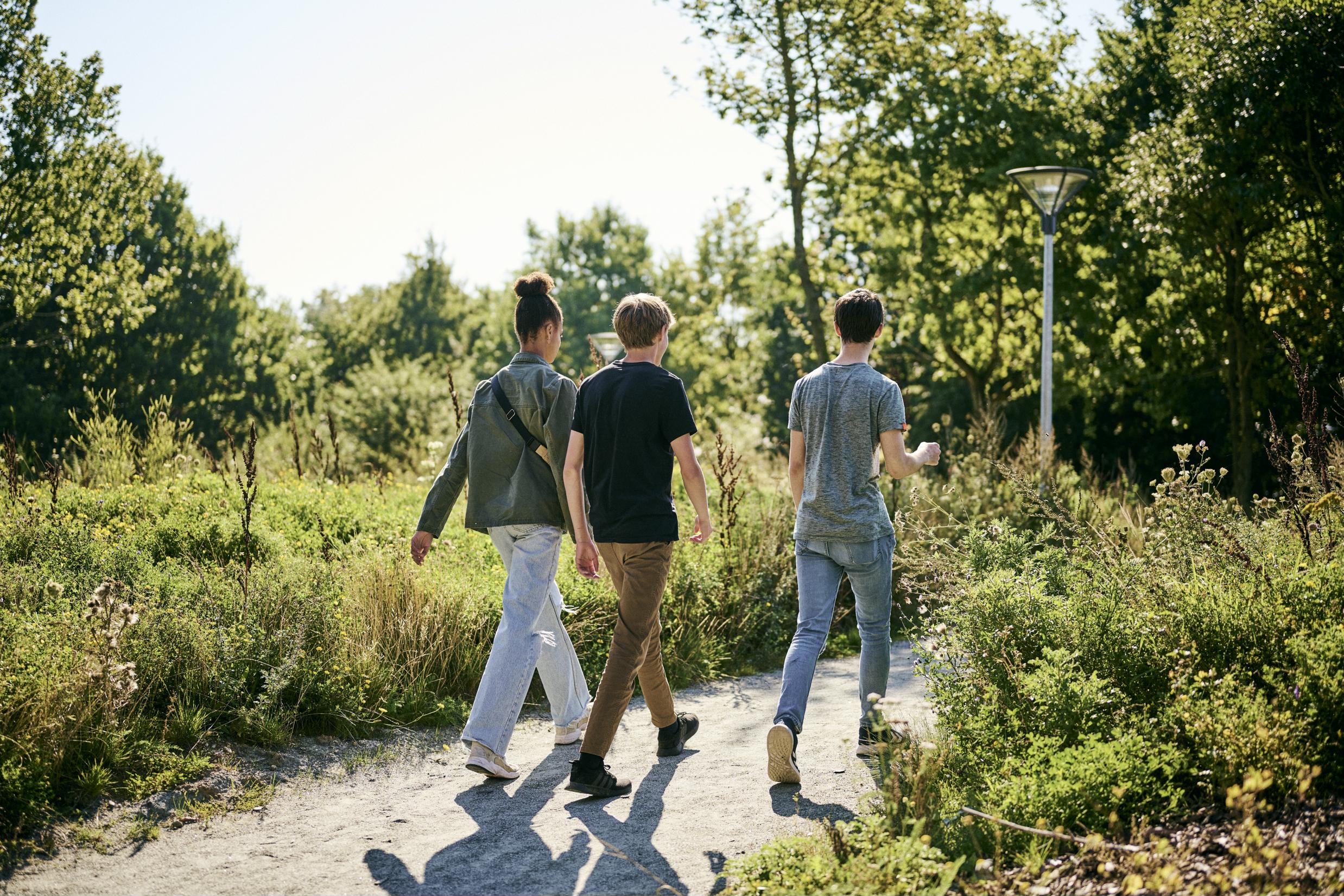3 elever trækker frisk luft i det grønne 'Vild med vilje'-område bag skolen på Skovvangen.
