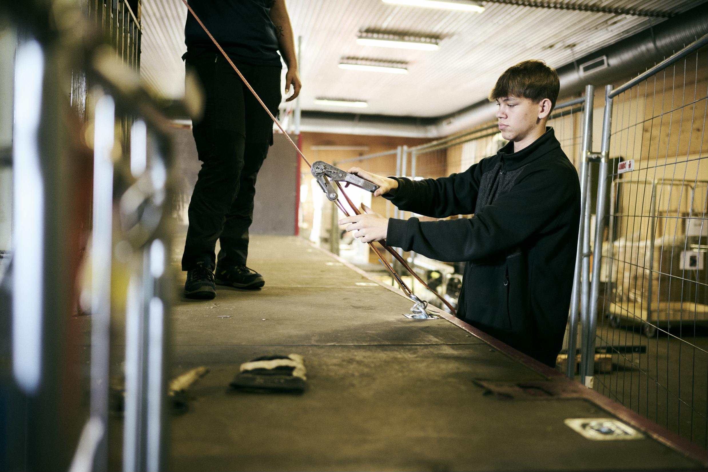 En logistikelev på lager- og terminaluddannelsen surrer lasten fast på ladet af en lastvogn.