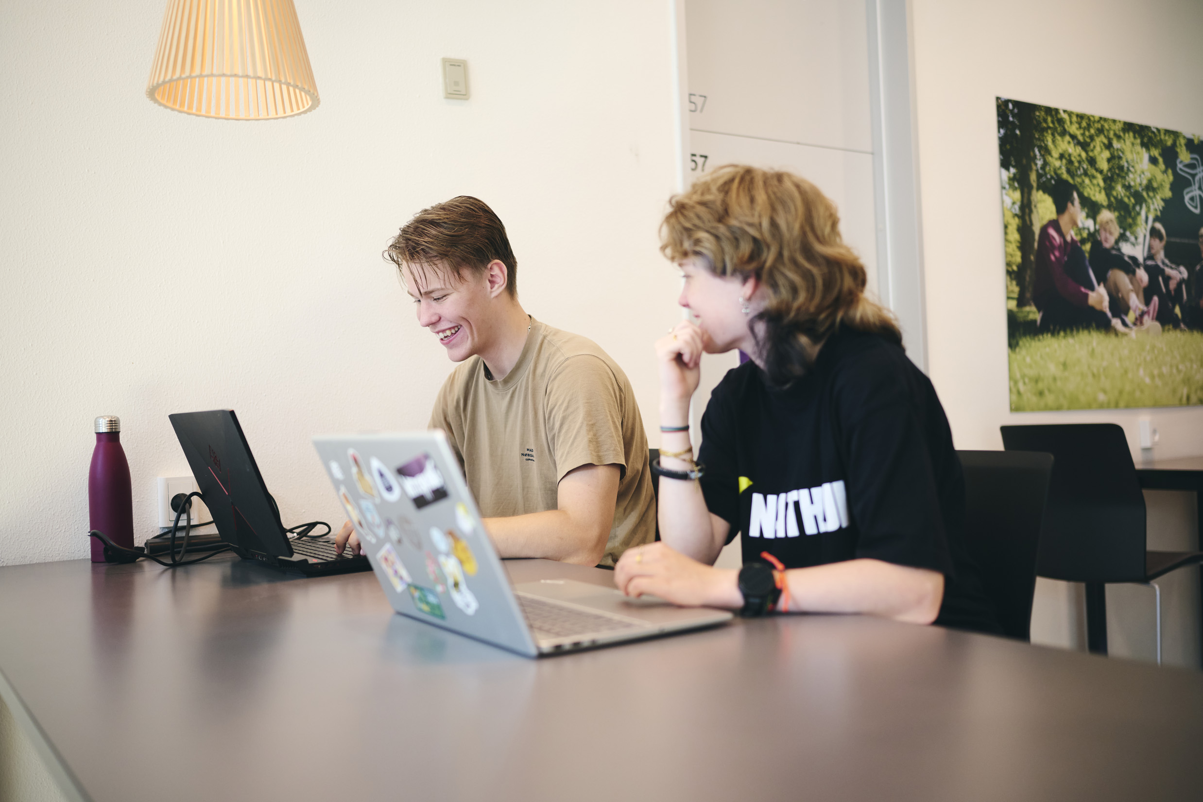 Der er gruppearbejde på HTX, og nogle af eleverne arbejder på deres bærbare ved de høje borde i fælleslokalet.