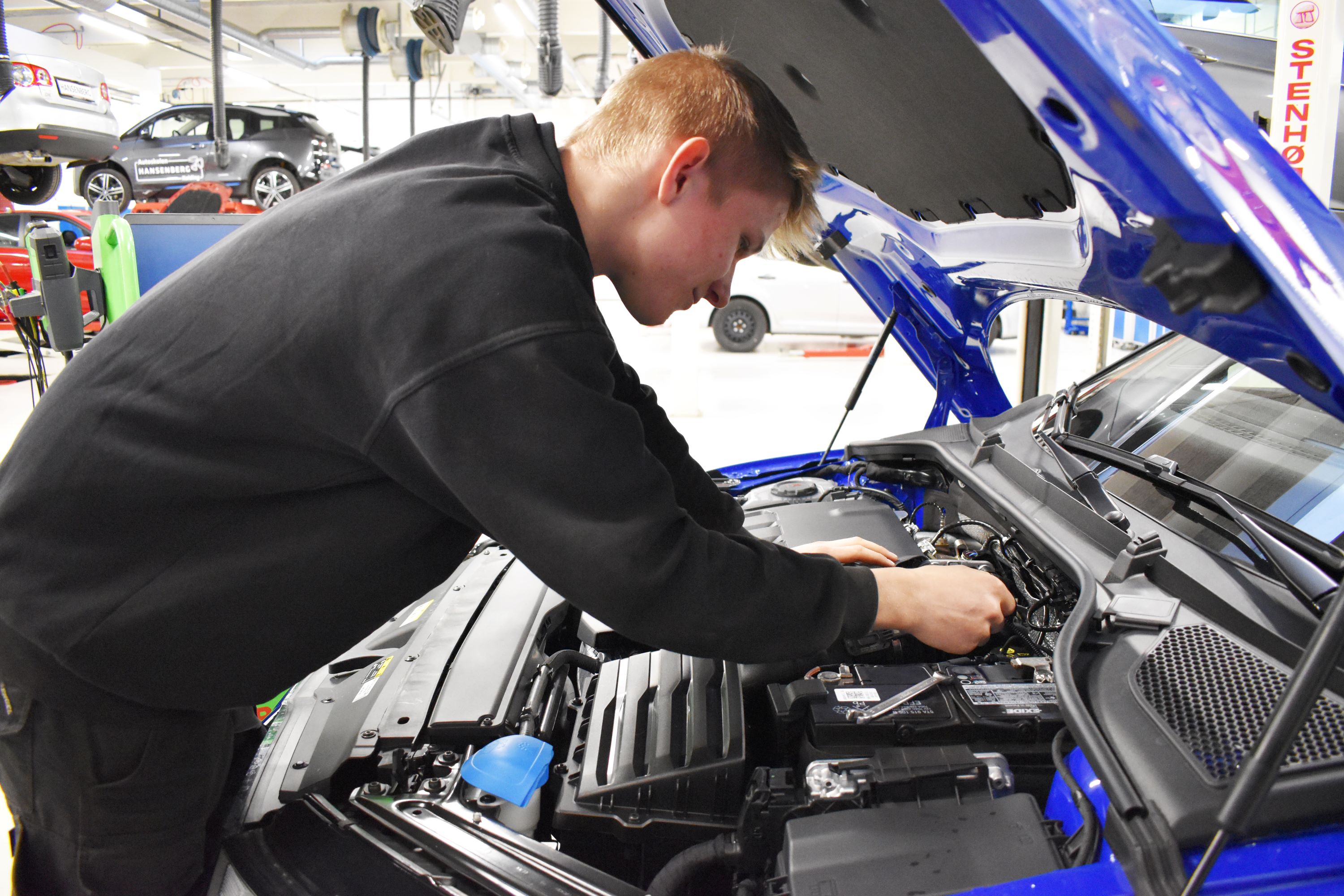 Personvognsmekanikerlærlingen træner på en elbil op til DM i Skills.