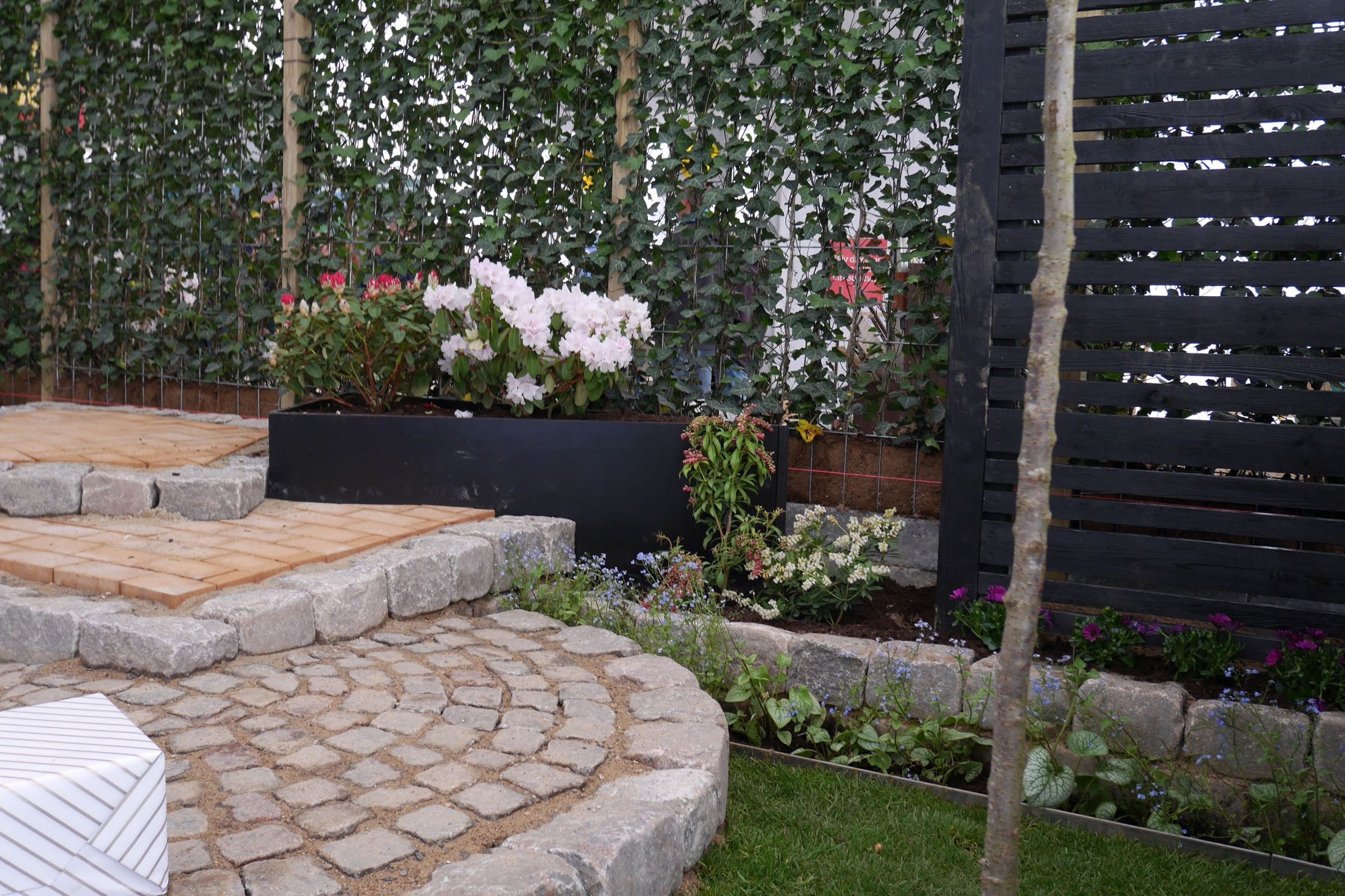 Anlægsgartnerelever har bygget flere niveauer i brosten og mursten, og har tilplantet bedene med blomster og buske.