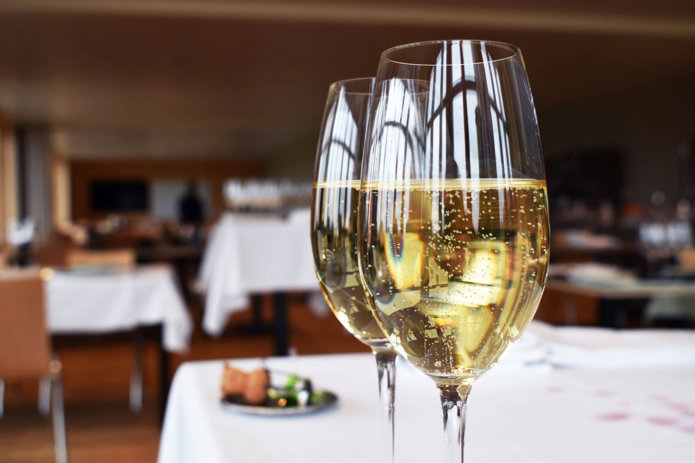 2 glas med boblende champagne, der netop er skænket af en tjenerelev.