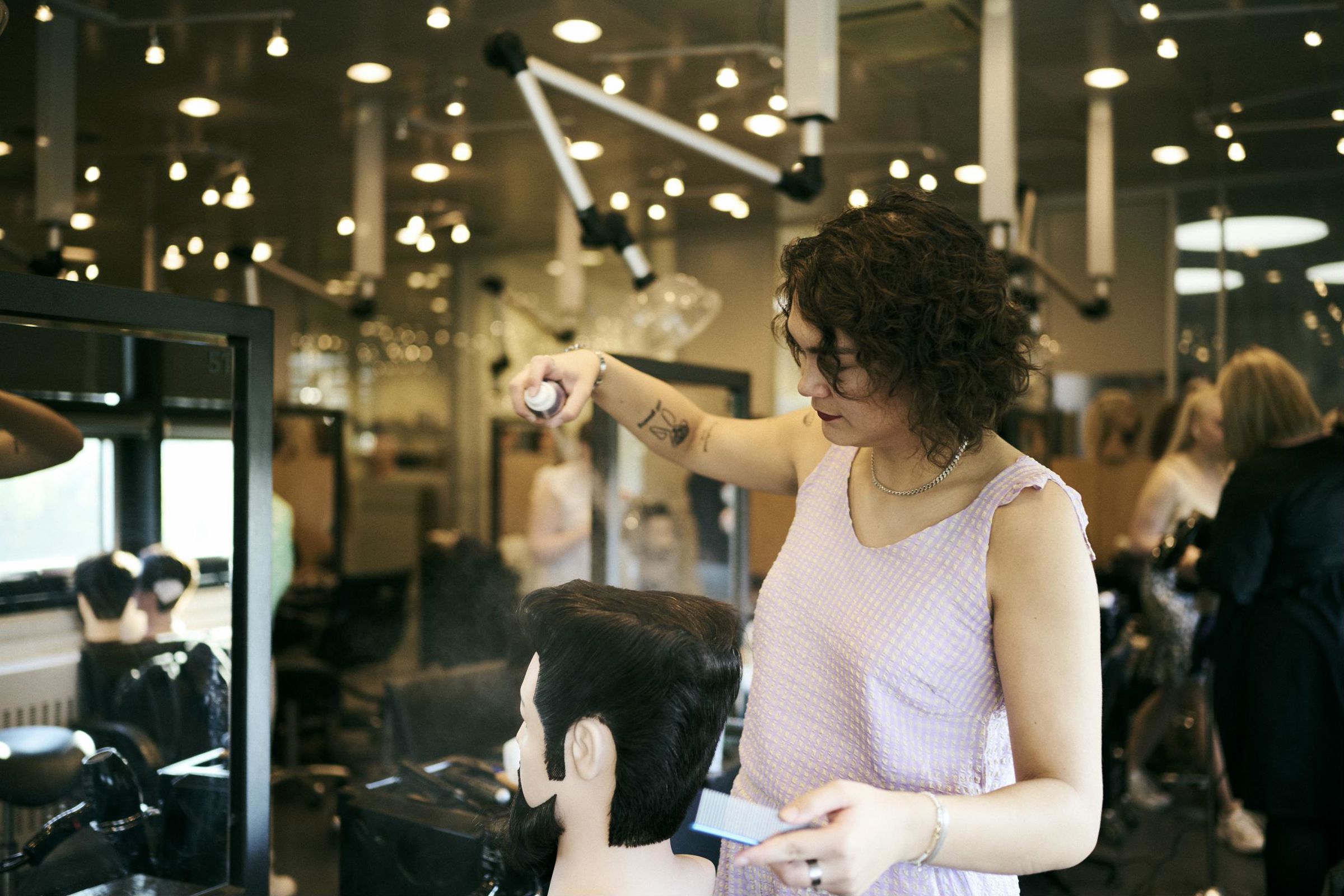 Frisørelev på Hansenberg sprayer hårspray på et øvelseshoved.