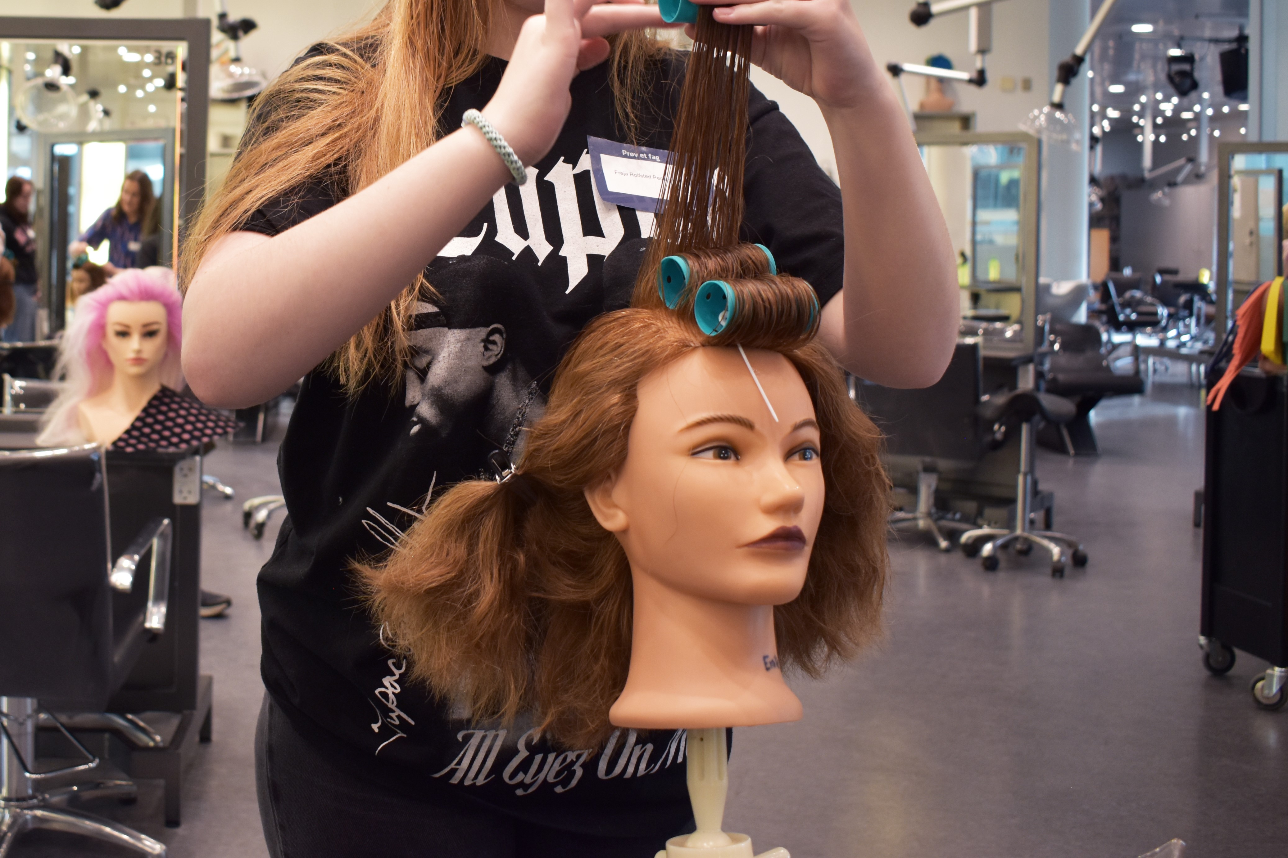 Til Prøv et fag for elever i 4.-10. klasse, er der en af deltagerne der ruller hår på curlers på et frisørhoved.