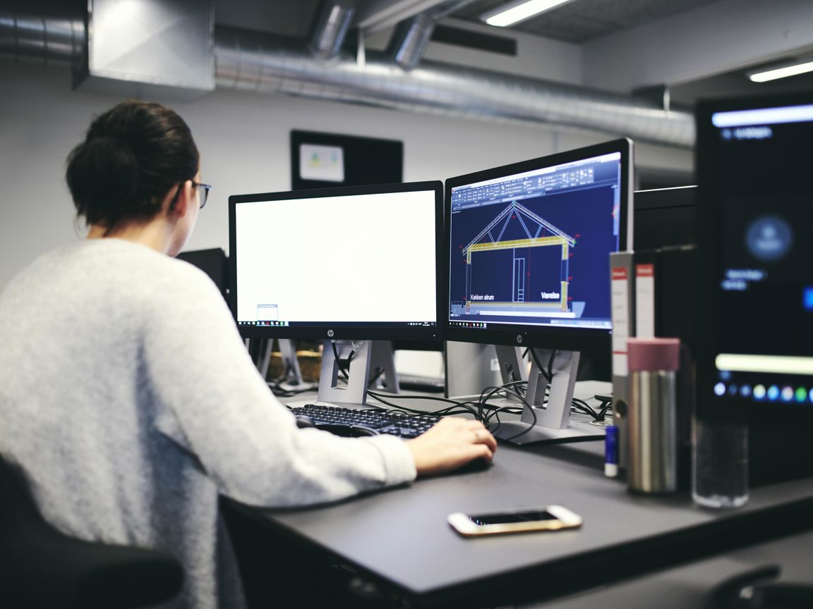 En teknisk designerelev er ved at designe en bygning inkl. mål på isolering mv.