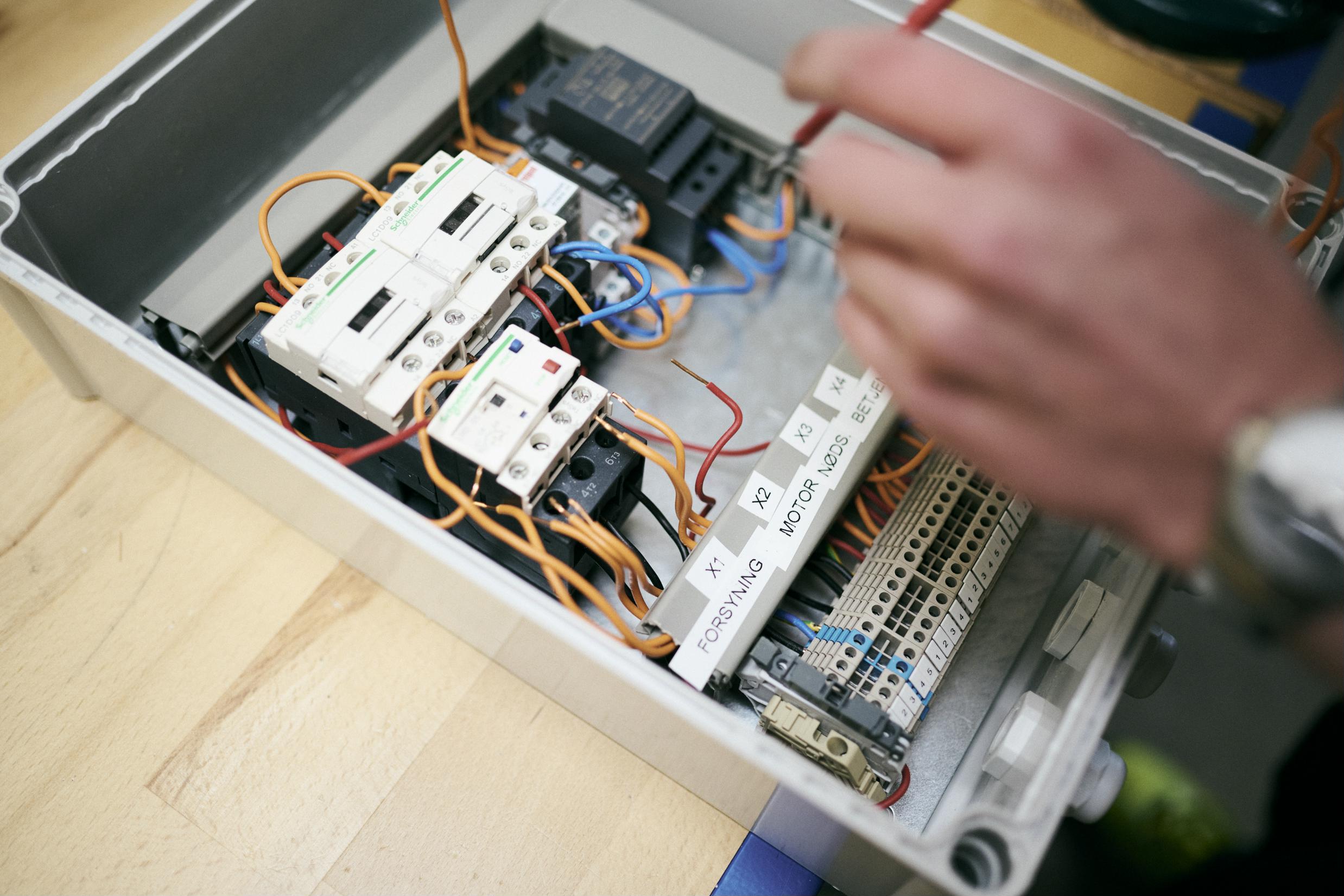 En elev på elektrikeruddannelsen arbejder med relæer i eltavlen.