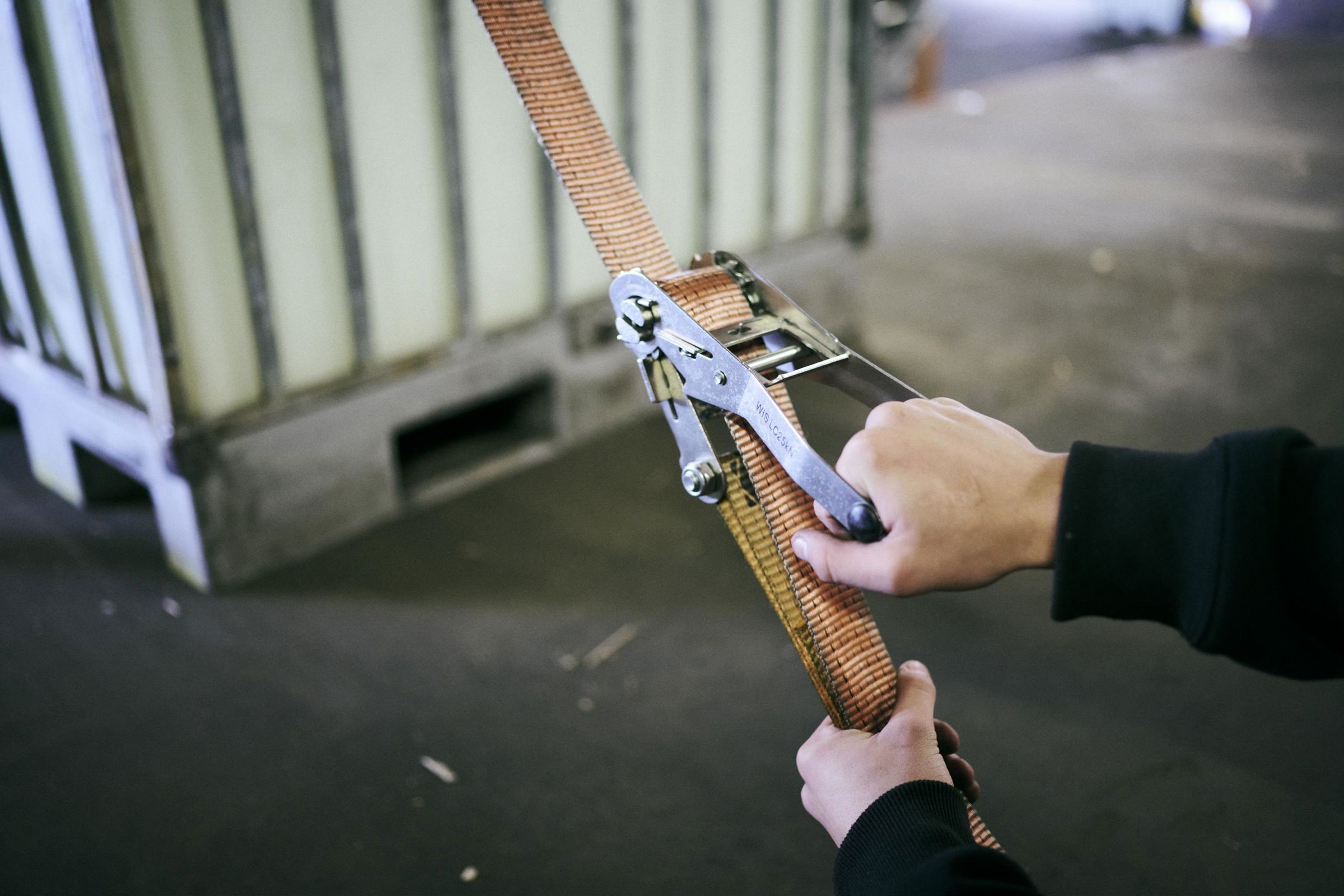 En elev på lager- og terminaluddannelsen surrer lasten fast på ladet af en lastvogn.