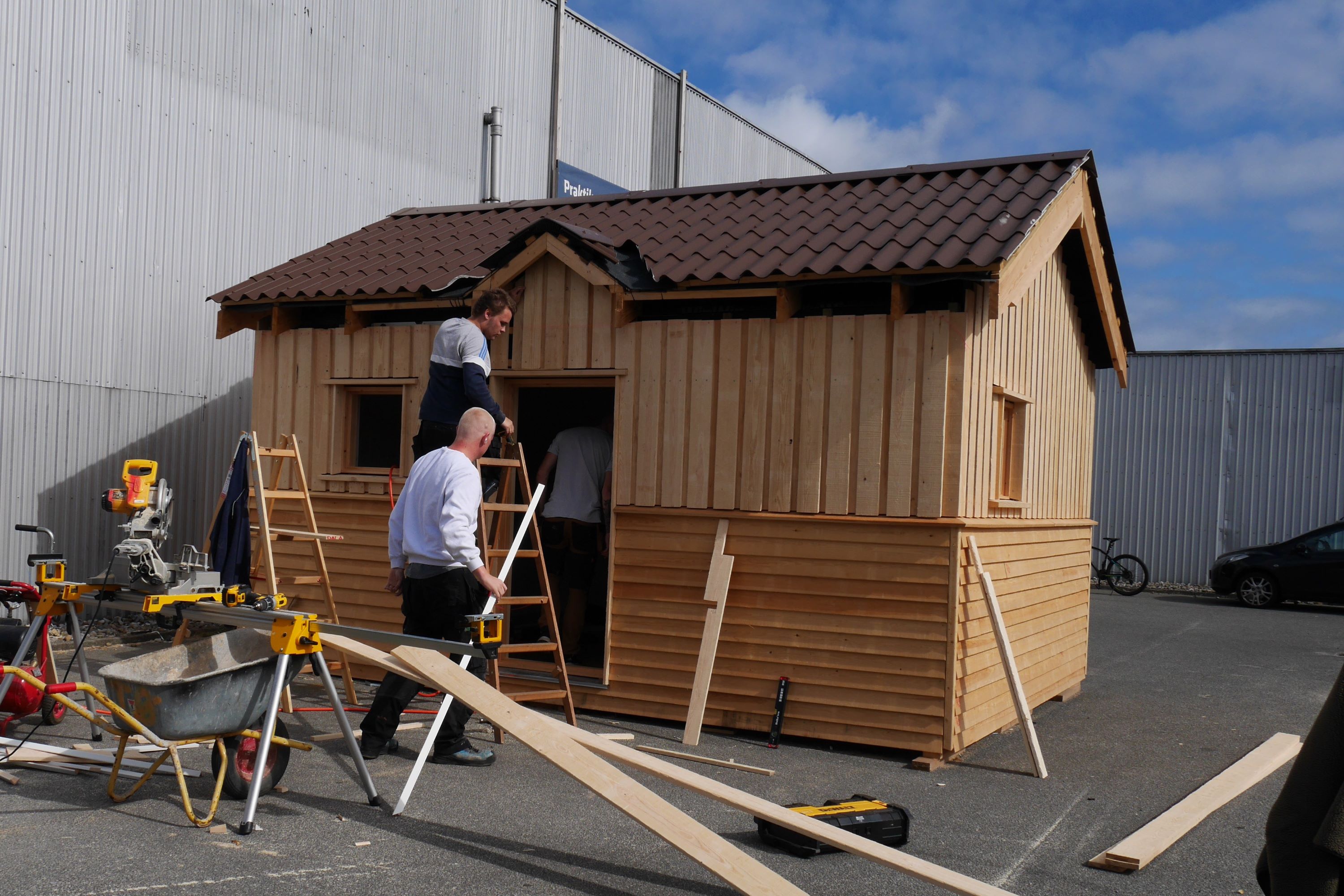 tre elever på Hansenbergs tømreruddannelse hjælpes ad med at bygge et annekshus i træ.