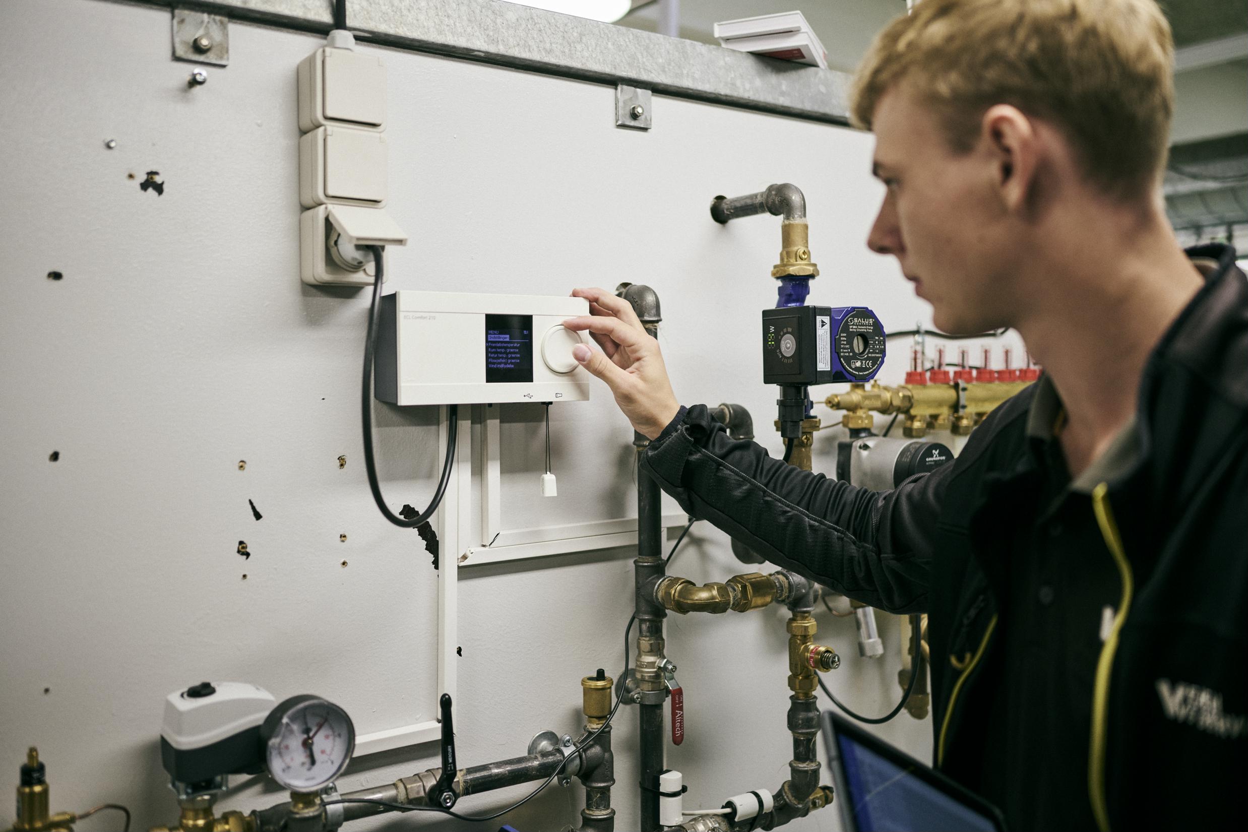 En lærling på vvs-energiuddannelsen indstiller et anlæg på Hansenbergs vvs-energiværksted.