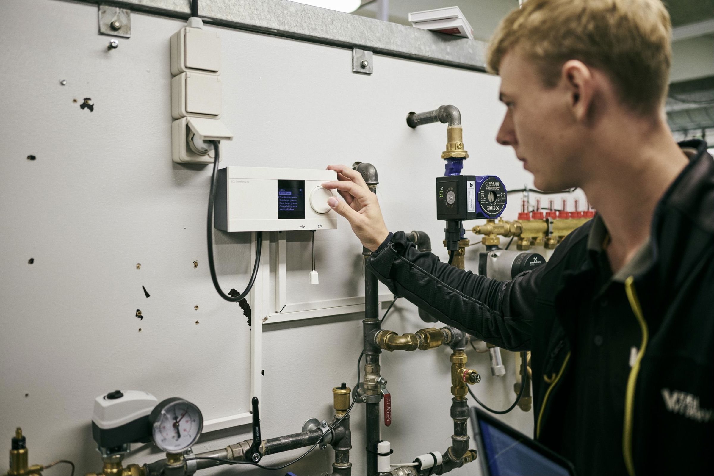 En lærling på vvs-energiuddannelsen indstiller et anlæg på Hansenbergs vvs-energiværksted.