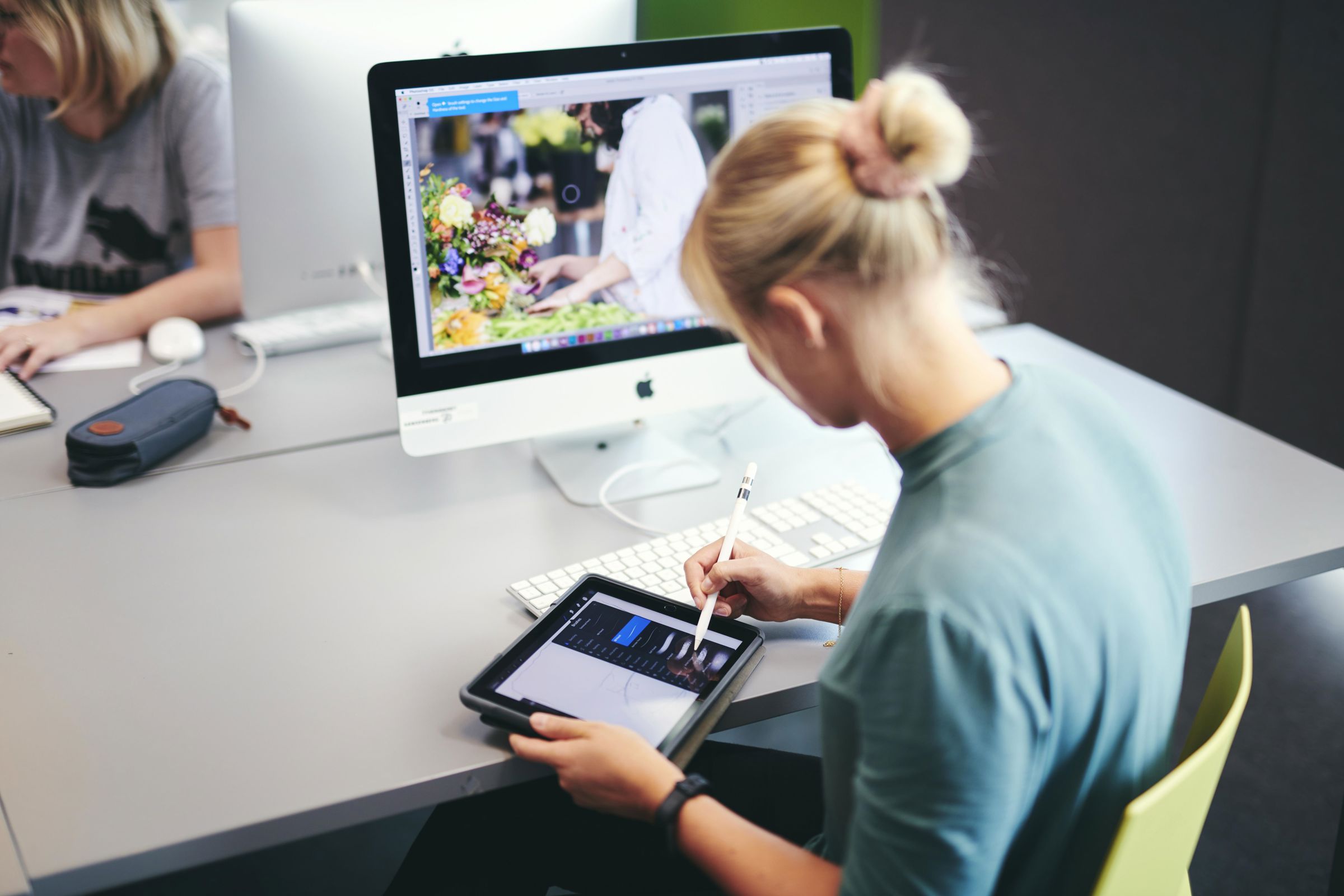 En kreativ mediegrafikerelev på Hansenberg arbejder med design på både iMac og iPad.