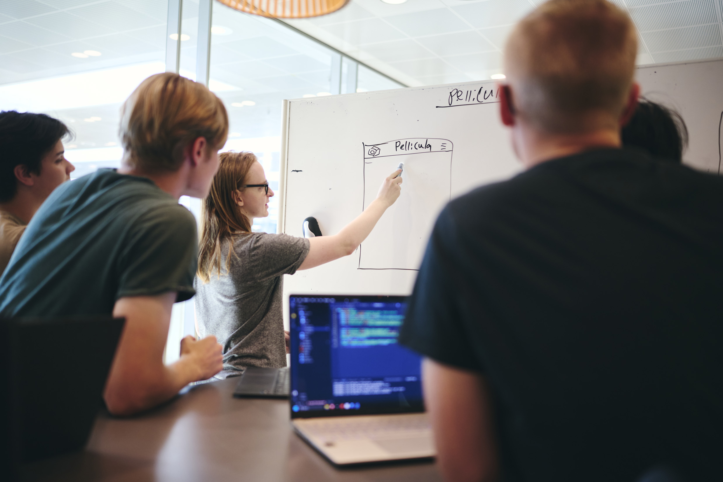 En gruppe elever på Hansenberg Tekniske Gymnasium har gruppearbejde i programmering, og en af eleverne skriver på tavlen.