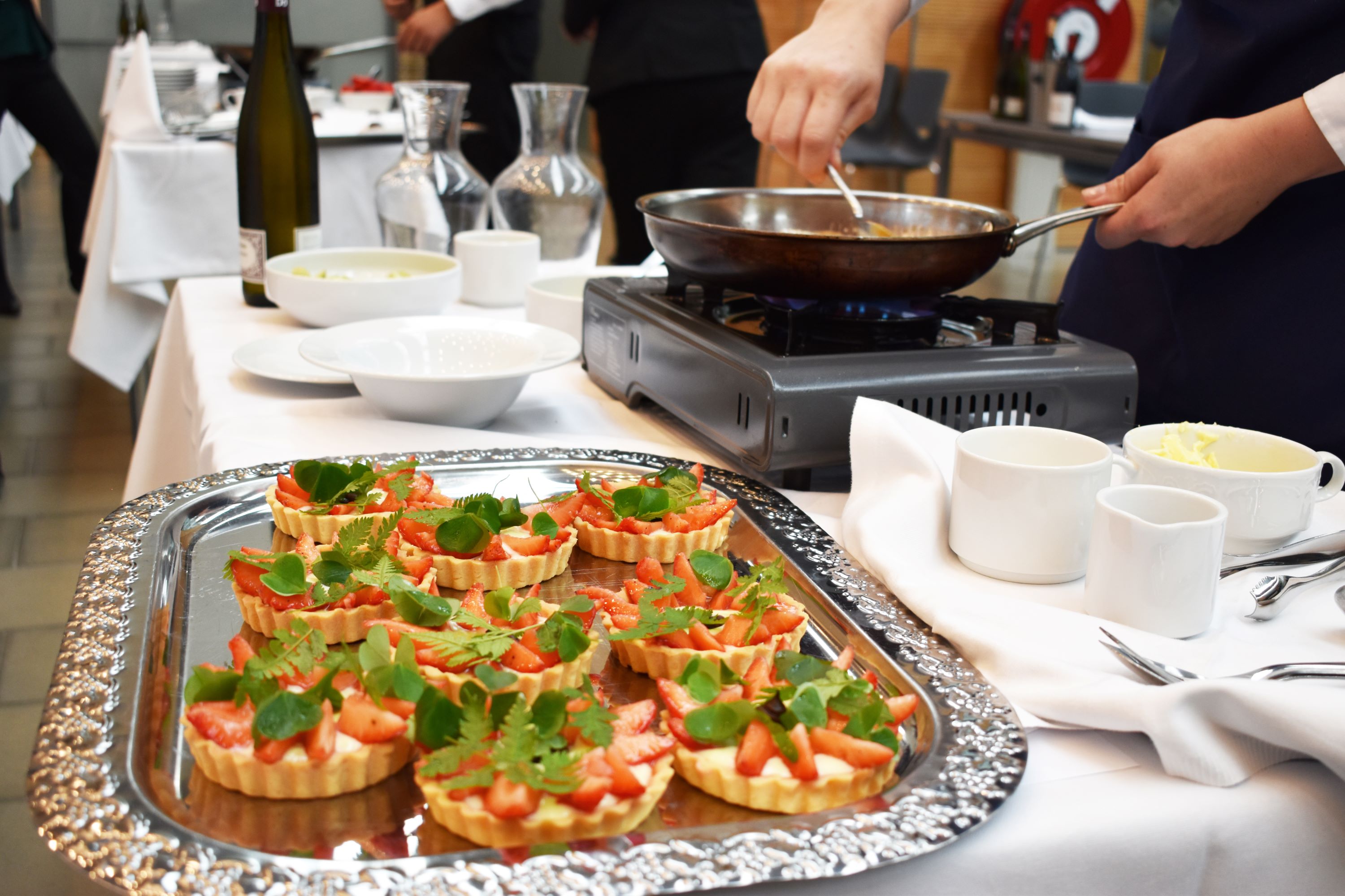 En tjenerelev har netop flamberet frugt, der skal serveres som en del af en delikat dessert.