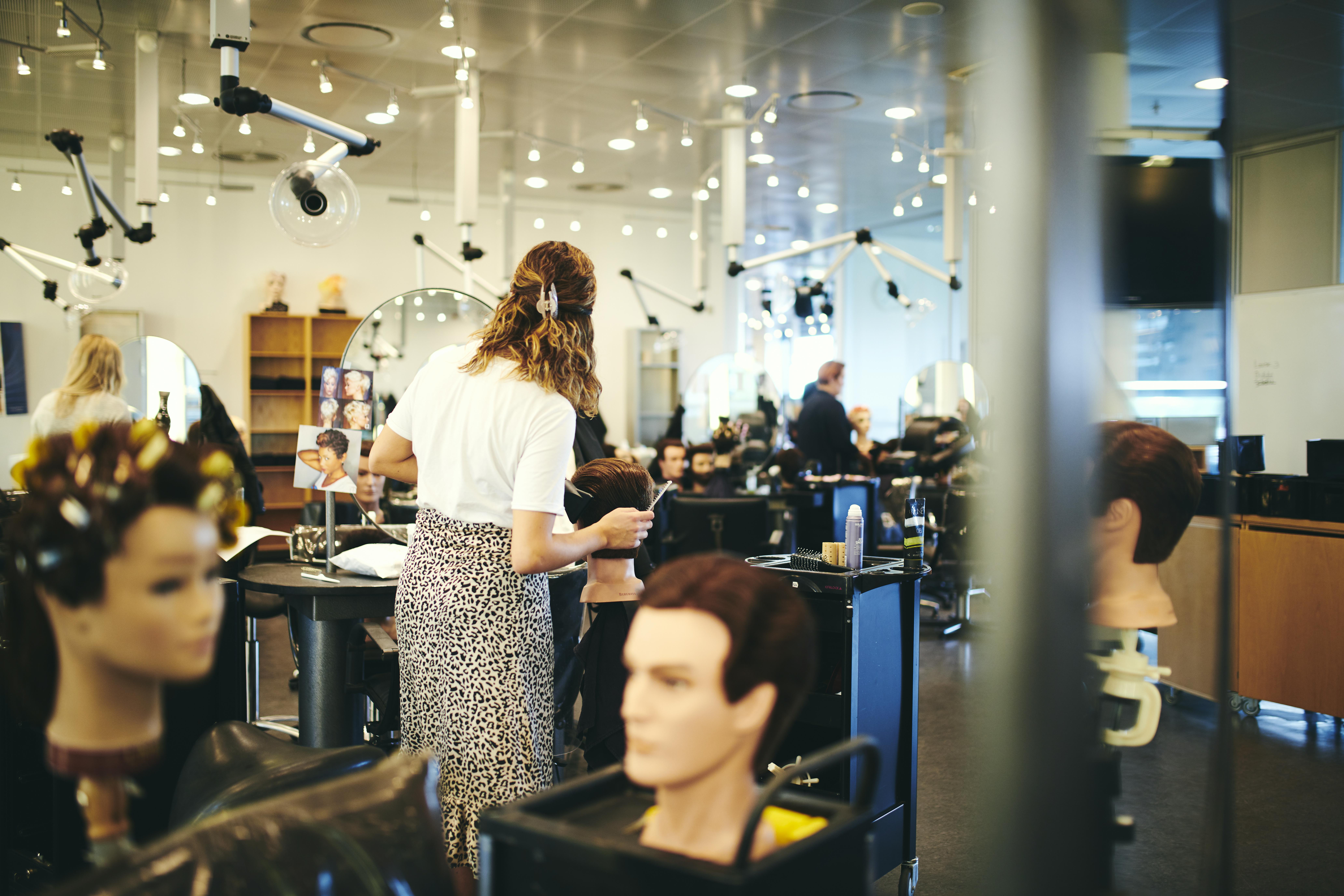 Frisørelev på Hansenberg ordner hår på et øvelseshoved i skolens frisørsalon.