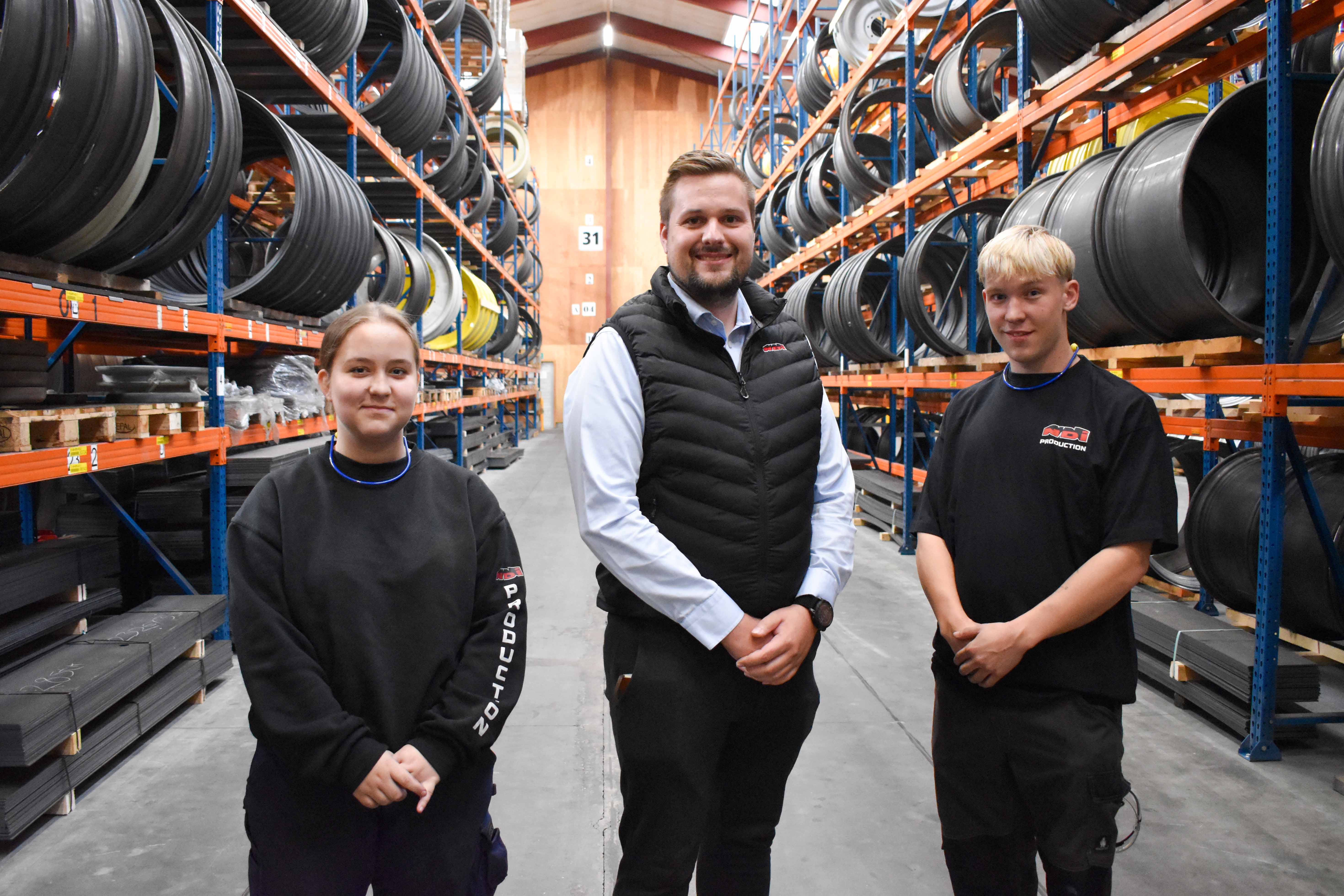 Malou Kraak, Emil Friis Osmann og Malthe Kobstrup står i en af NDI Wheel Productions store lagerhaller.