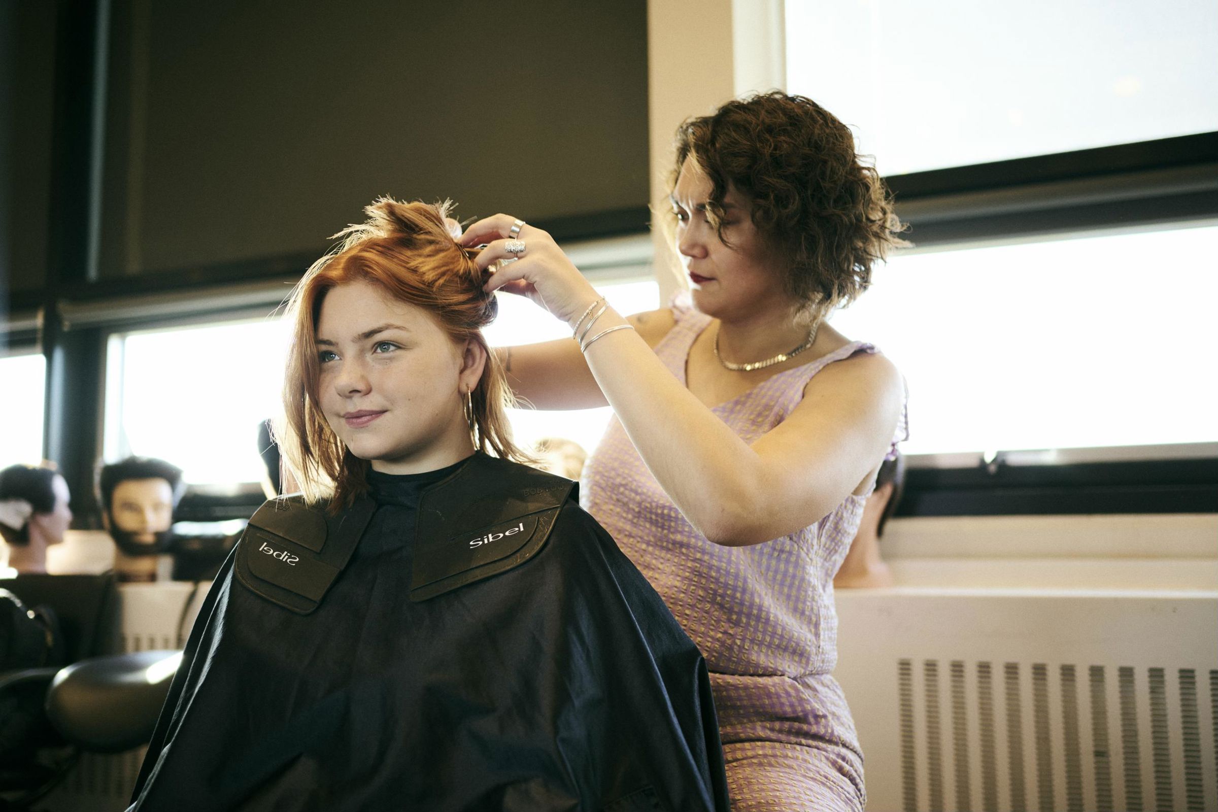 En pige sidder model og får ordnet hår af en frisørelev i Salon Hansenberg.