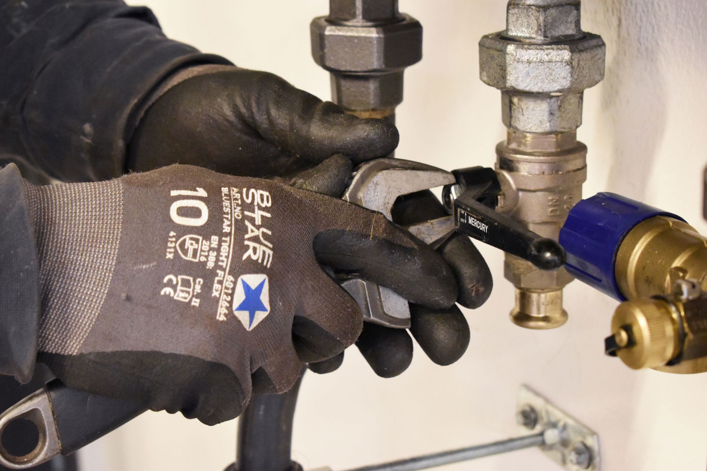 Et har hænder i arbejdshandsker arbejder i skolens VVS-energiværksted.