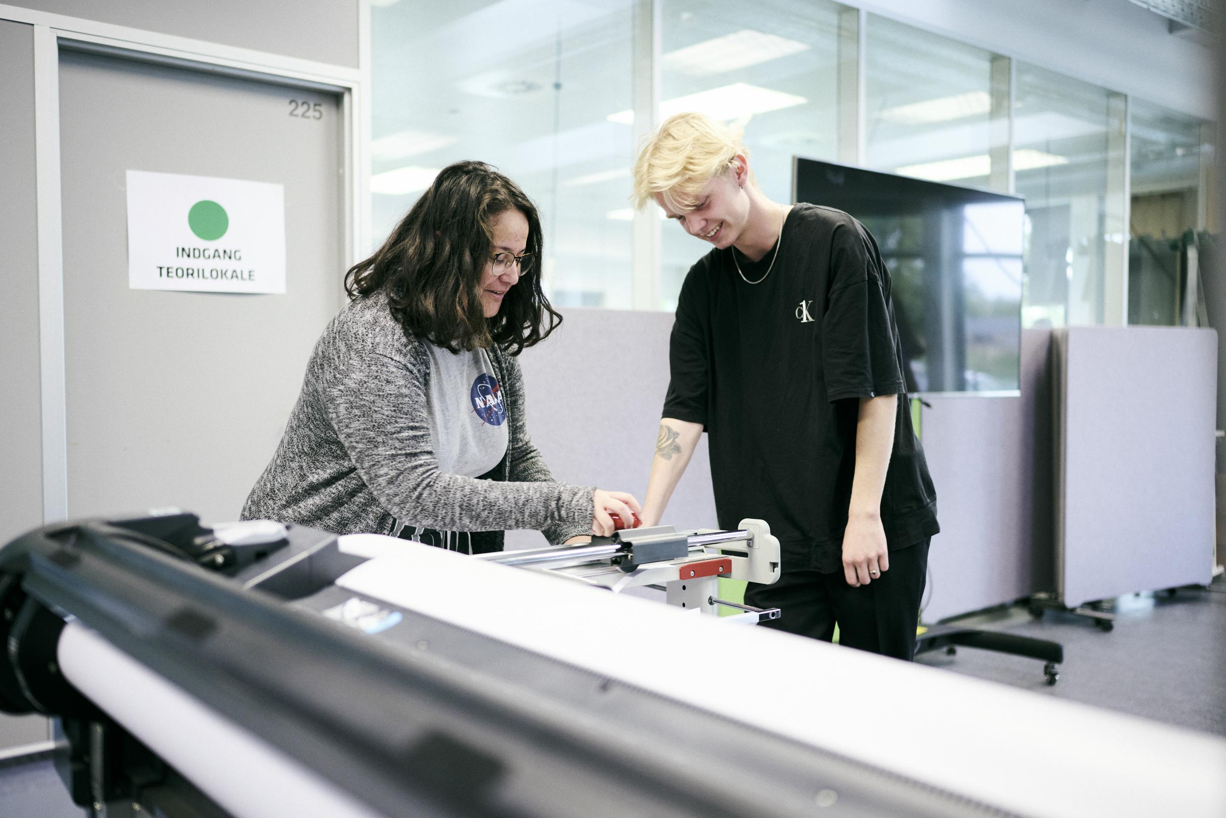 to elever på uddannelsen til teknisk designer tilskærer en hustegning i storformat.